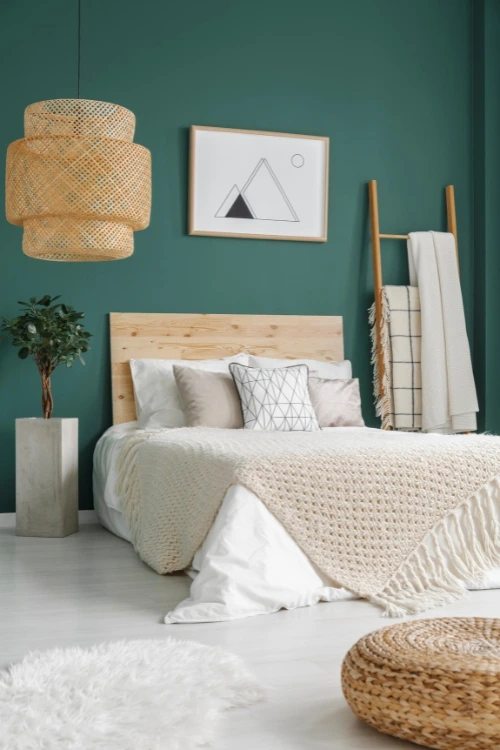 a bed with a blanket and a plant in front of it.